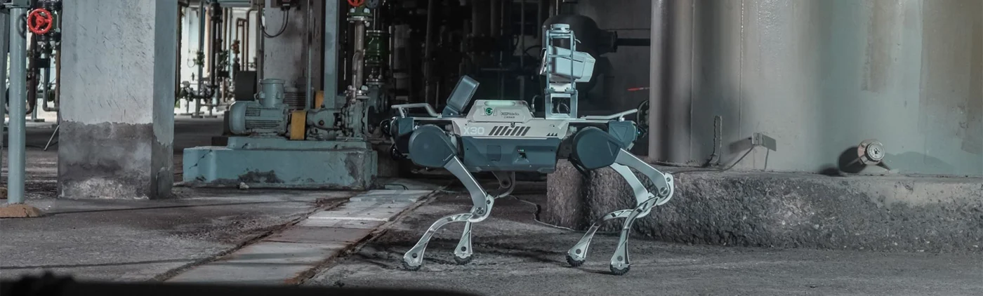 X30 quadruped with a mounted sensor payload in an industrial pipe-and-tank environment.