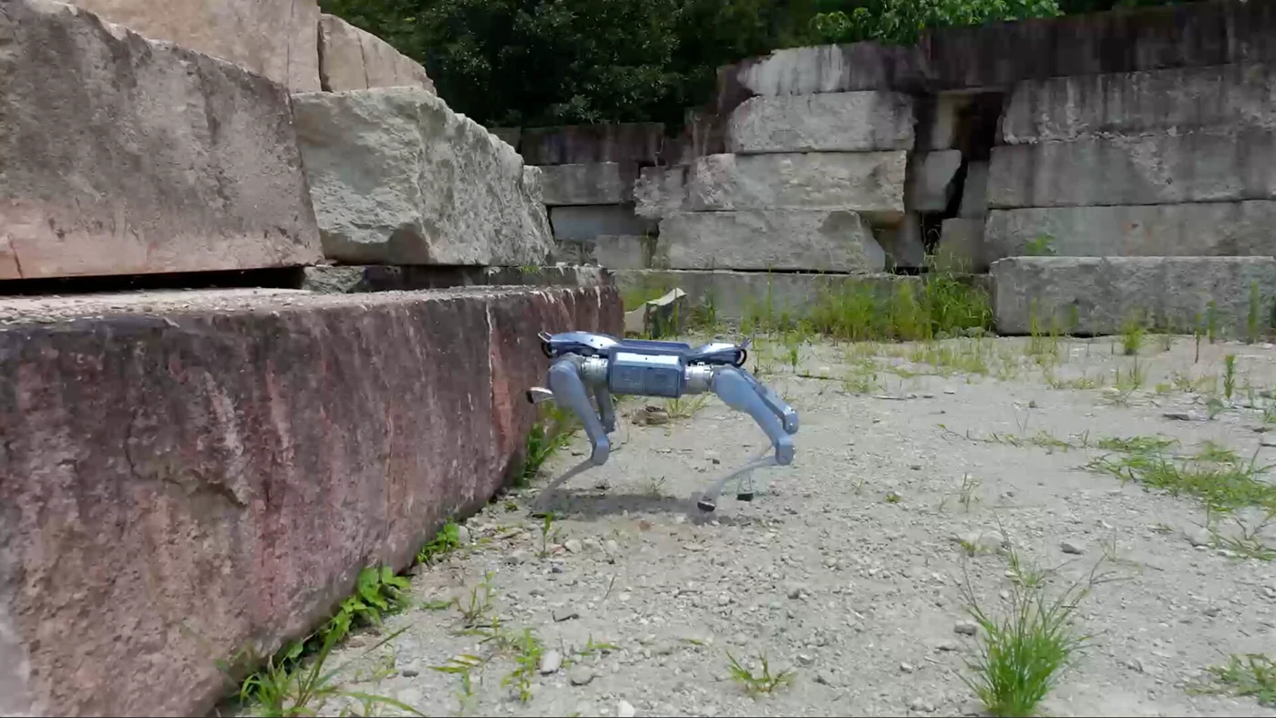 Legged A2 on uneven ground beside large stone ledges.