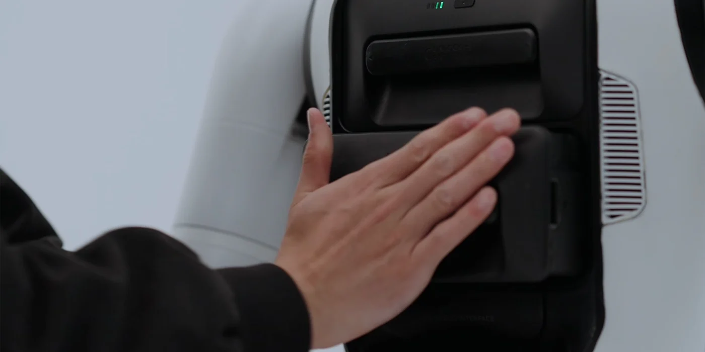 Close-up of the battery being handled; official hot-swap feature section.
